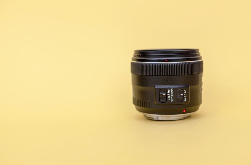 Close-up of a photo of a camera lens on a yellow background.