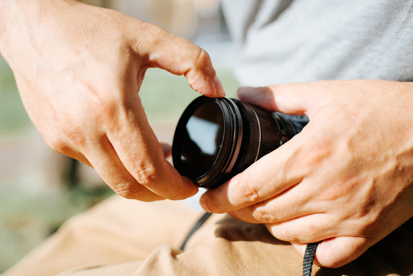 Close-up of a photographer's male hands putting a professional protective filter on the camera