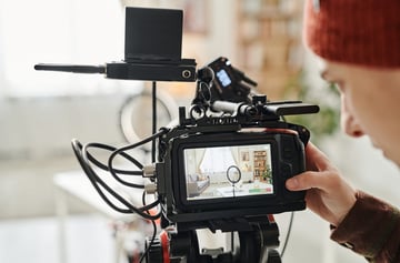 Screen of camera and hand of cameraman standing in spacious living room