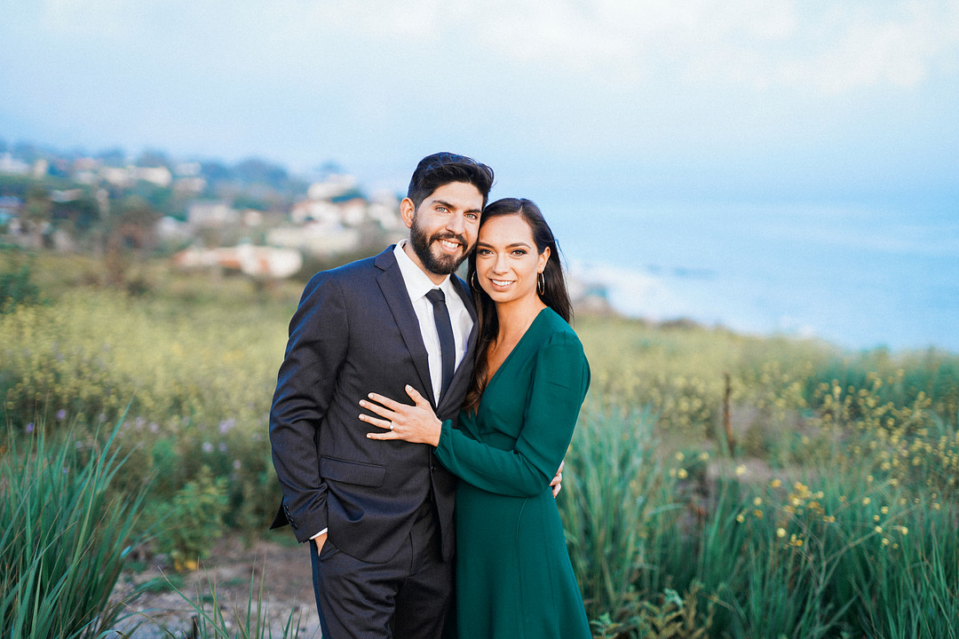 Engagement photo of couple in a field by the water